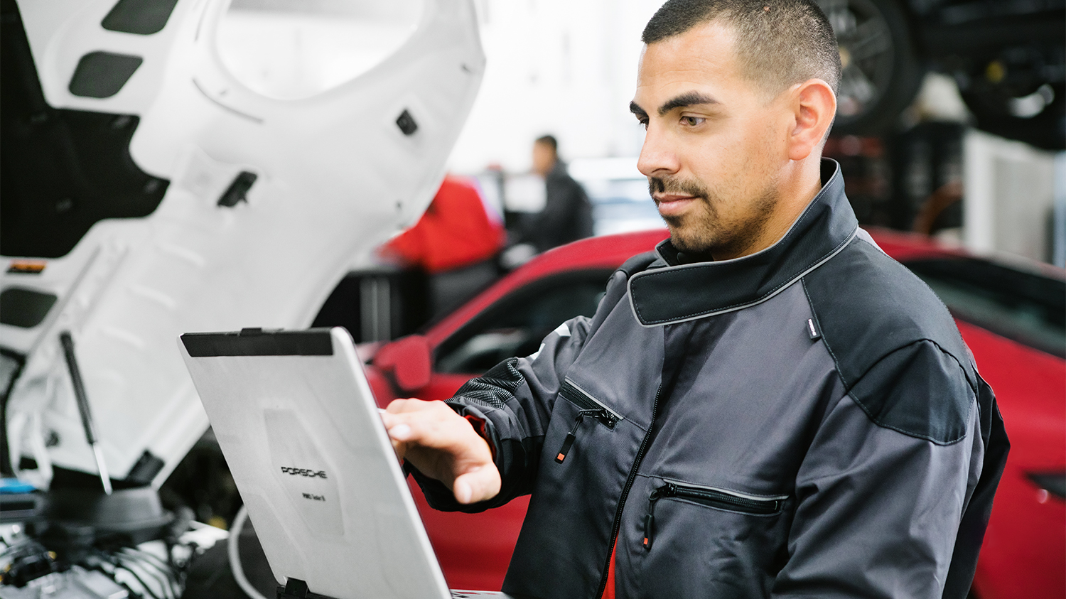 Ein Service Techniker arbeitet an seinem Laptop, in der Werkstatt. 